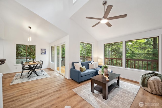 living area featuring light wood-type flooring, baseboards, ceiling fan, and high vaulted ceiling