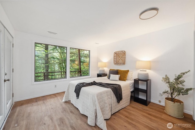 bedroom with baseboards, wood finished floors, and visible vents