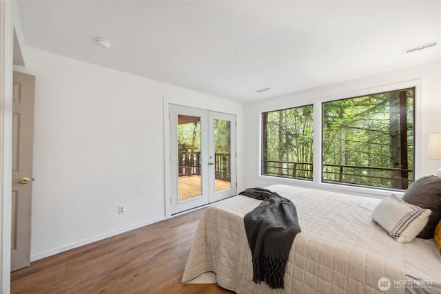 bedroom featuring french doors, wood finished floors, access to outside, and multiple windows