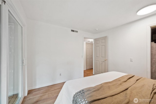 bedroom featuring visible vents, light wood-style floors, and baseboards