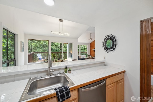 kitchen with stainless steel dishwasher, tile countertops, a sink, and a healthy amount of sunlight