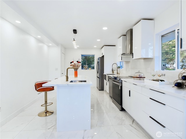 kitchen featuring modern cabinets, a kitchen bar, wall chimney exhaust hood, stainless steel appliances, and a sink