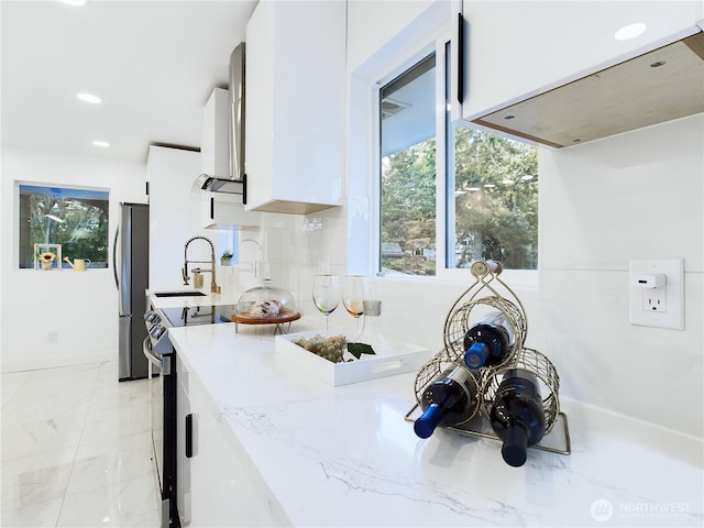 kitchen featuring light stone counters, white cabinetry, appliances with stainless steel finishes, marble finish floor, and recessed lighting