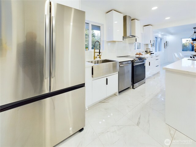 kitchen featuring marble finish floor, modern cabinets, wall chimney range hood, and appliances with stainless steel finishes