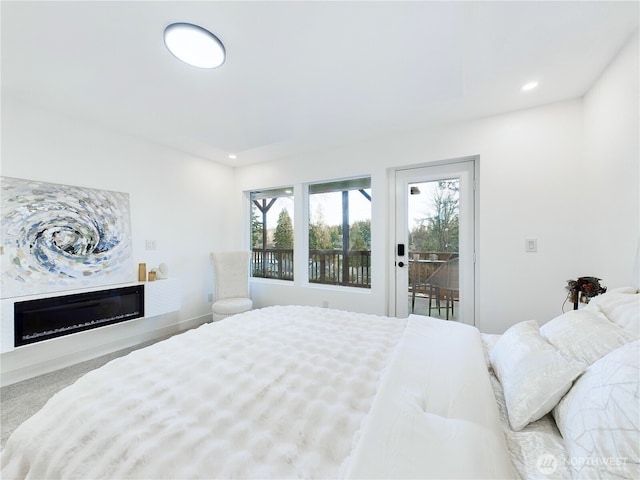 bedroom with a glass covered fireplace, recessed lighting, and access to outside