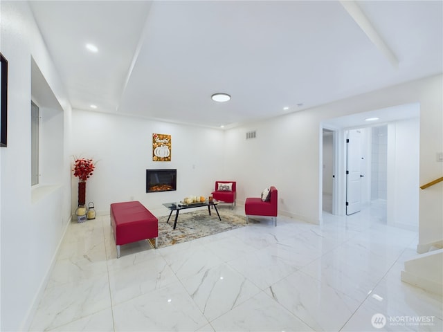 living area featuring marble finish floor, visible vents, recessed lighting, and a glass covered fireplace