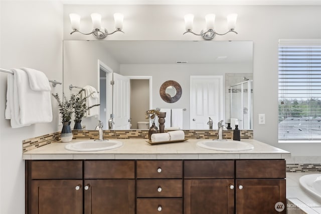 bathroom featuring a sink, a shower stall, and tasteful backsplash