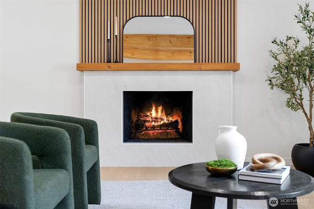 sitting room featuring wood finished floors and a warm lit fireplace