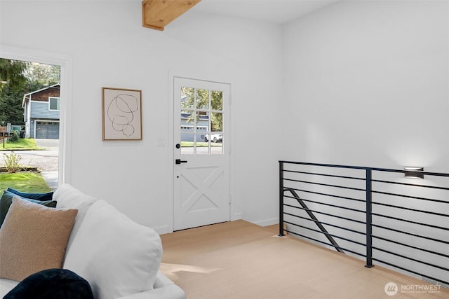 doorway to outside featuring light wood-style flooring and beamed ceiling