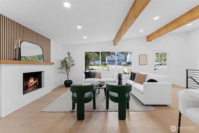 living area featuring wood finished floors, lofted ceiling with beams, a large fireplace, and recessed lighting