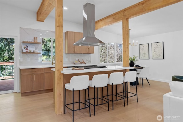 kitchen featuring open shelves, island exhaust hood, light wood finished floors, backsplash, and beam ceiling