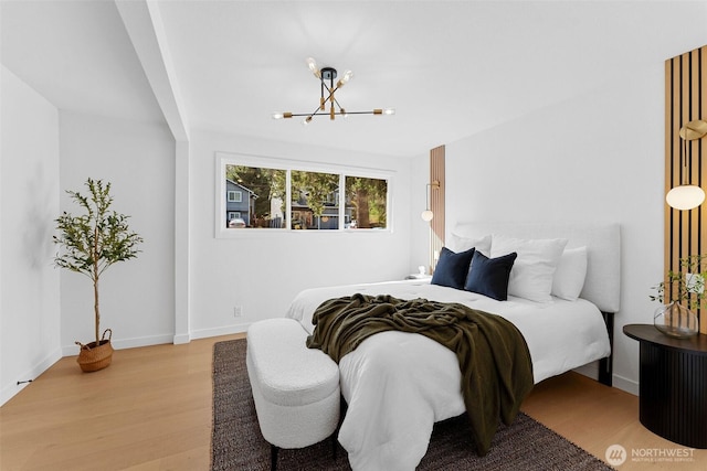 bedroom featuring baseboards, a notable chandelier, and wood finished floors