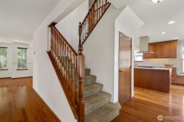 stairway featuring wood finished floors, a wealth of natural light, and recessed lighting