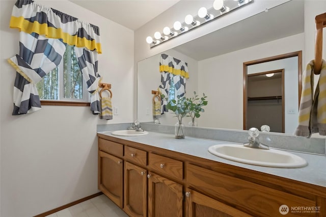 full bath featuring double vanity, baseboards, and a sink