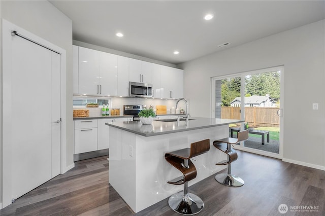 13815 Brookdale Ln E Unit 107, Tacoma, WA 98445 - kitchen with tasteful backsplash, a breakfast bar, dark wood-style floors, stainless steel appliances, and a sink