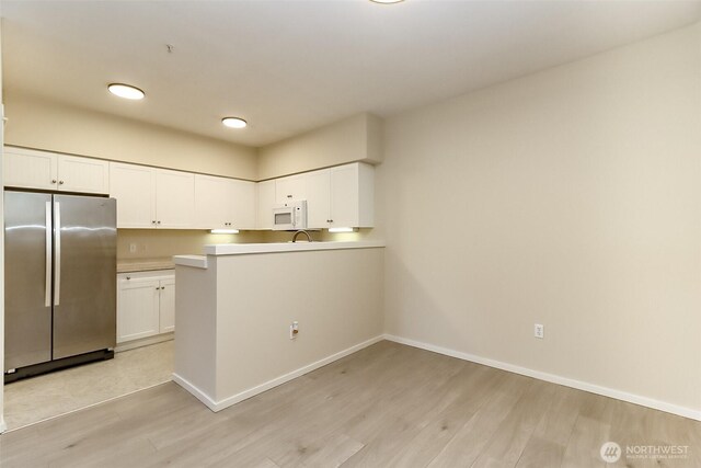 15026 40th Ave W Unit 7-203, Lynnwood, WA 98087 - kitchen with white cabinetry, light wood-type flooring, white microwave, and freestanding refrigerator