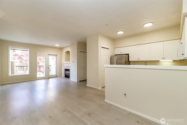 15026 40th Ave W Unit 7-203, Lynnwood, WA 98087 - unfurnished living room featuring baseboards, recessed lighting, light wood finished floors, and a glass covered fireplace