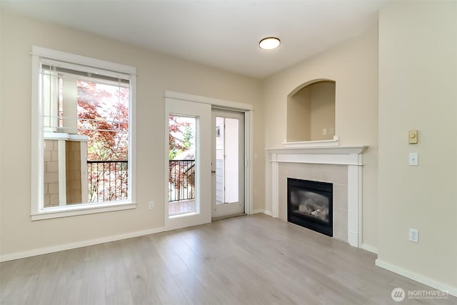 15026 40th Ave W Unit 7-203, Lynnwood, WA 98087 - unfurnished living room featuring wood finished floors, a tiled fireplace, and baseboards