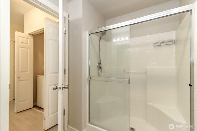 15026 40th Ave W Unit 7-203, Lynnwood, WA 98087 - full bathroom with washer / dryer, a stall shower, and wood finished floors