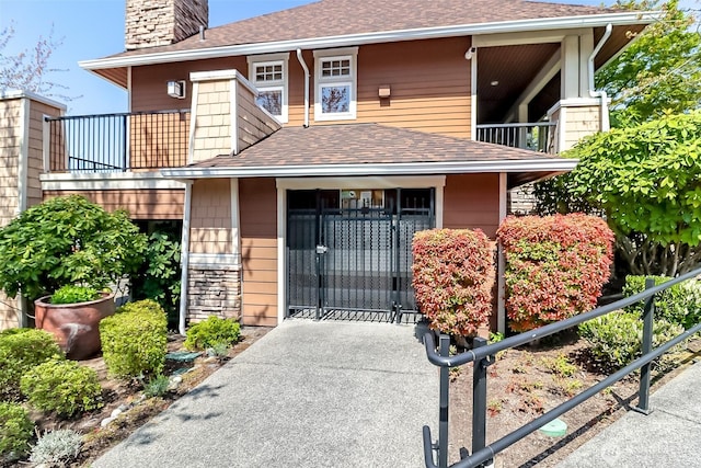 15026 40th Ave W Unit 7-203, Lynnwood, WA 98087 - view of front of house with a balcony, a chimney, a gate, a shingled roof, and fence private yard
