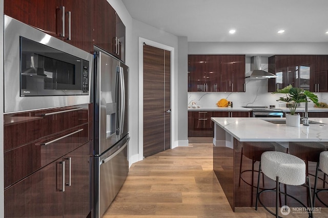 1515 141st St E Unit 72, Tacoma, WA 98445 - kitchen featuring appliances with stainless steel finishes, wall chimney exhaust hood, modern cabinets, light wood-style floors, and a breakfast bar area