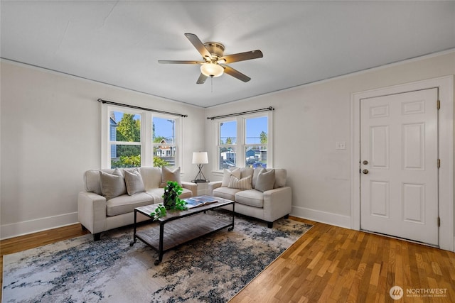 living area featuring baseboards, a ceiling fan, and wood finished floors
