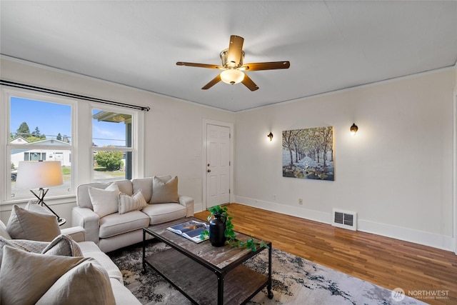 living area featuring baseboards, ceiling fan, visible vents, and wood finished floors