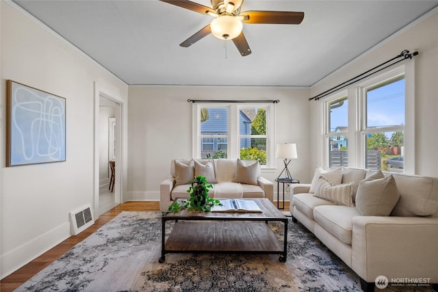 living room featuring ceiling fan, visible vents, crown molding, wood finished floors, and baseboards