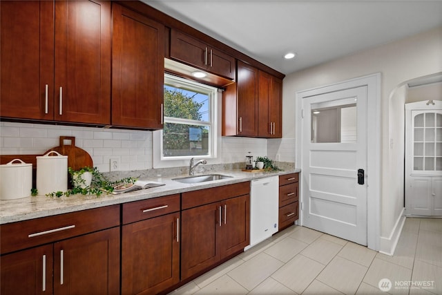 kitchen with dishwasher, light tile patterned floors, light stone counters, a sink, and backsplash
