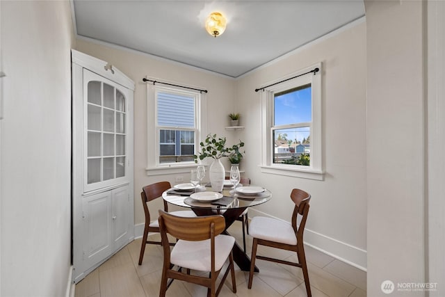 dining space featuring a healthy amount of sunlight, baseboards, and crown molding