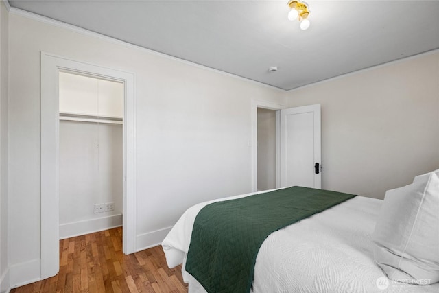bedroom featuring crown molding, baseboards, a closet, and wood finished floors
