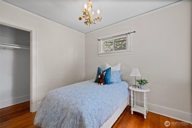 bedroom featuring an inviting chandelier, baseboards, and wood finished floors