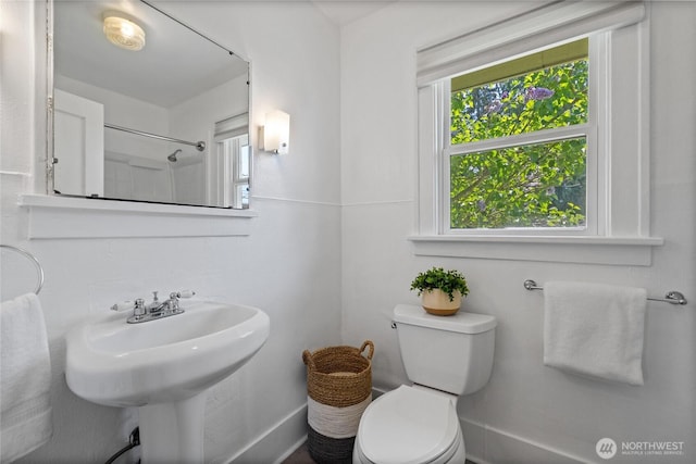 bathroom featuring a sink, baseboards, plenty of natural light, and toilet