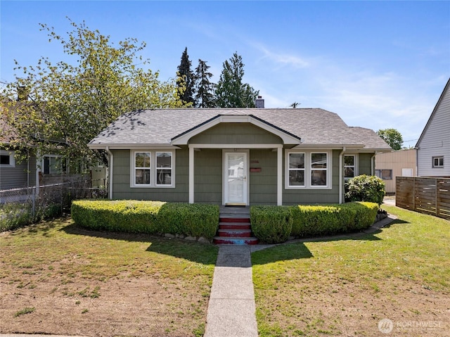 bungalow featuring fence, a chimney, roof with shingles, and a front lawn
