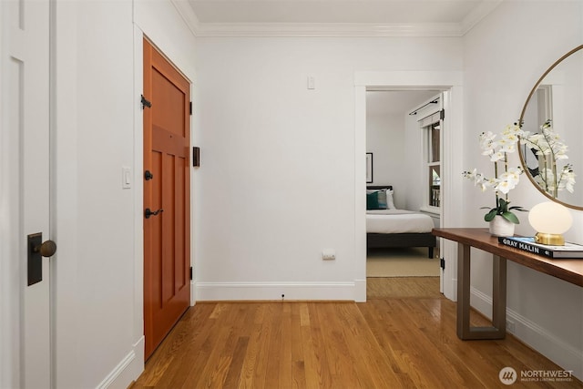 hall featuring light wood-style floors, baseboards, and ornamental molding