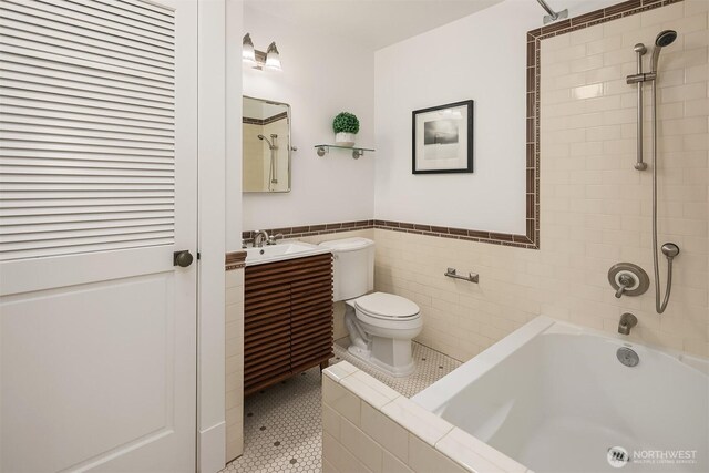 full bath with toilet, tile walls, wainscoting, vanity, and tile patterned flooring