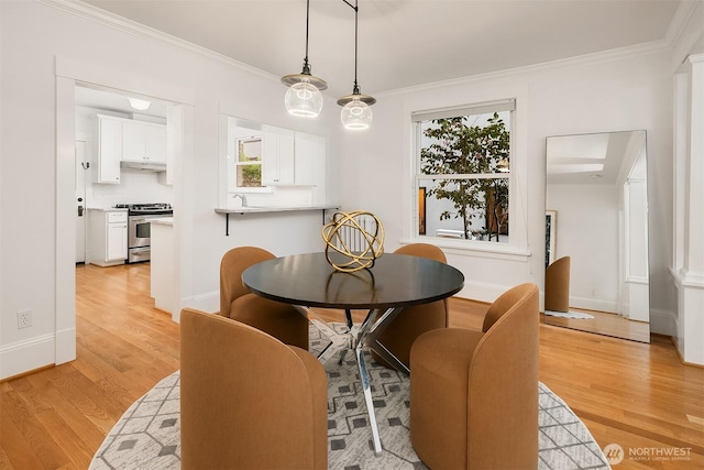 dining area featuring light wood-style floors, crown molding, and baseboards