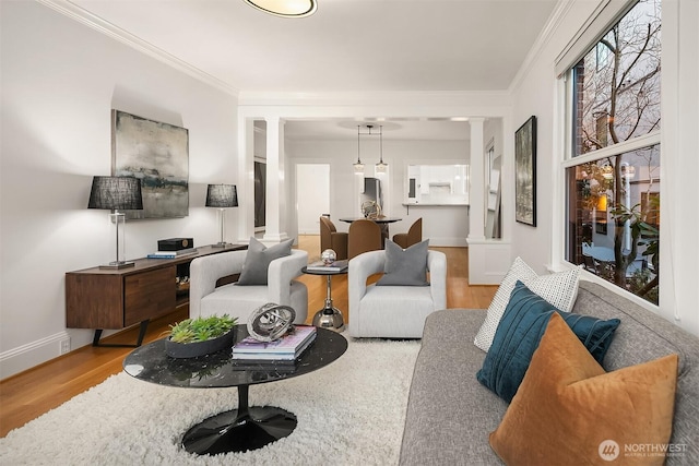 living area with ornamental molding, baseboards, ornate columns, and wood finished floors