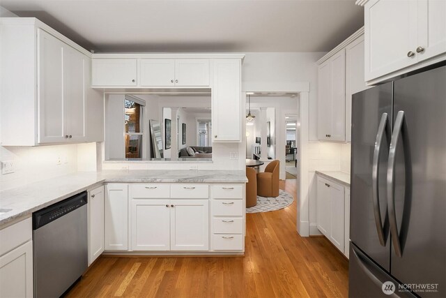 kitchen with white cabinets, light wood-type flooring, decorative backsplash, and appliances with stainless steel finishes