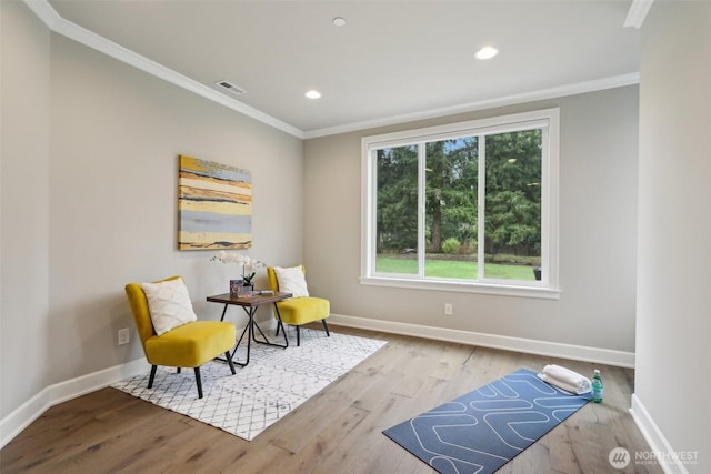 living area featuring ornamental molding, baseboards, and wood finished floors