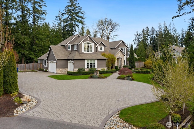 view of front of property with a garage, stone siding, fence, a front lawn, and driveway