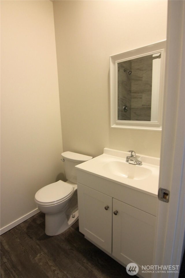 bathroom featuring vanity, toilet, baseboards, walk in shower, and wood finished floors