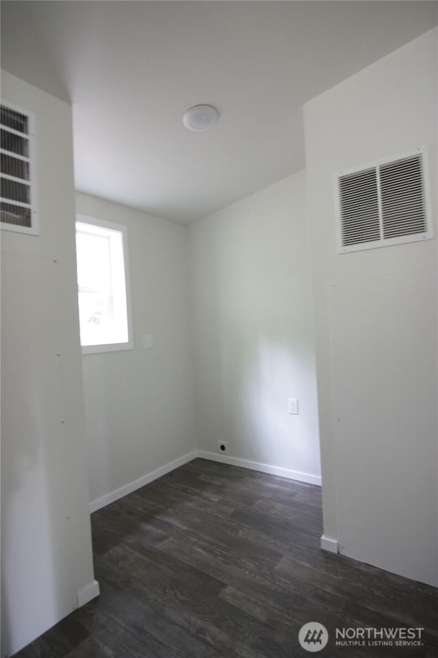 spare room with dark wood-type flooring, baseboards, and visible vents