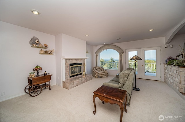 living area with recessed lighting, light carpet, arched walkways, visible vents, and a tile fireplace