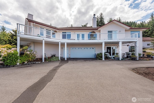 view of front of house with a chimney, a garage, and driveway