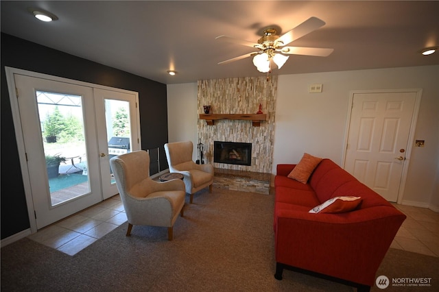 living area with a stone fireplace, a ceiling fan, and light tile patterned floors