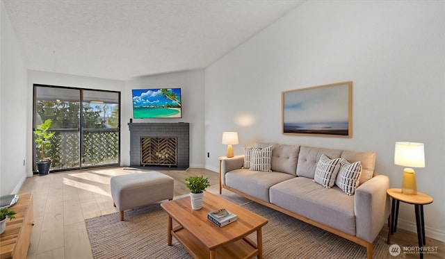 living room with a brick fireplace, baseboards, and hardwood / wood-style floors