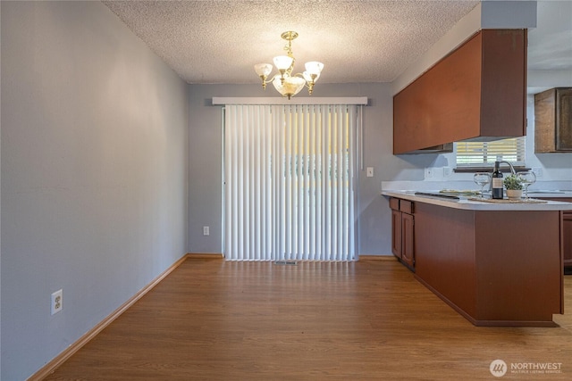 1023 S 88th St, Tacoma, WA 98444 - kitchen with a notable chandelier, light wood-style flooring, a textured ceiling, light countertops, and brown cabinetry