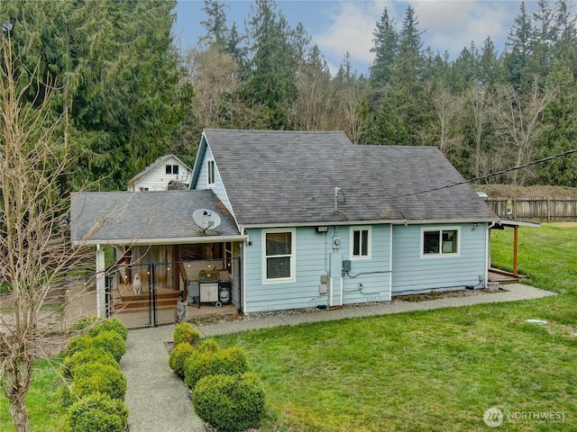 view of front of house featuring a front lawn, fence, and roof with shingles