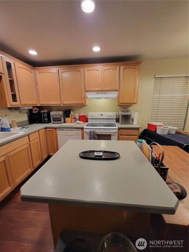 kitchen with white appliances, a kitchen island, under cabinet range hood, light countertops, and light brown cabinets